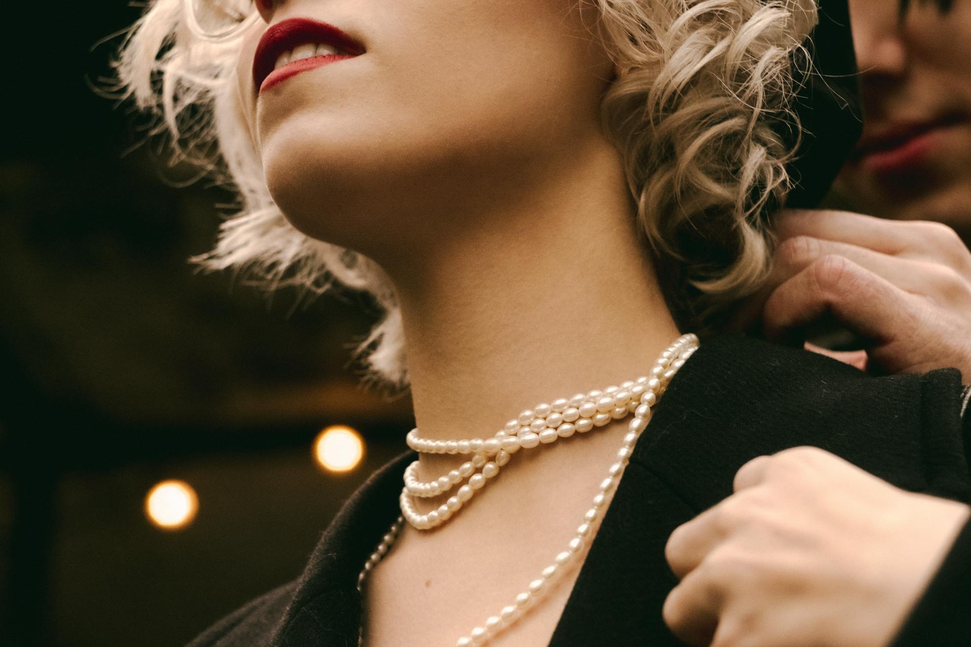 A man putting a pearl necklace around a woman's neck | Source: Pexels