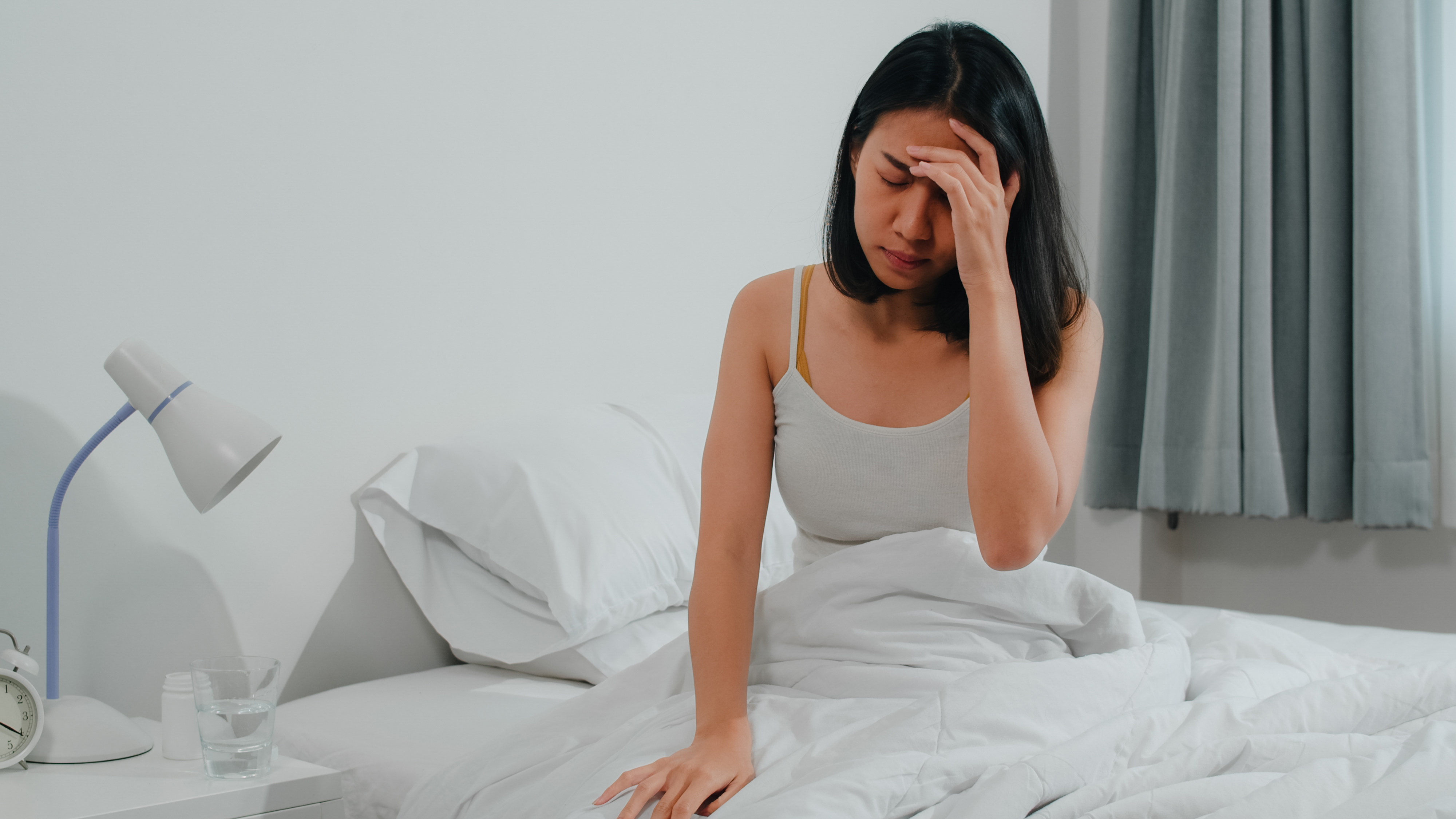 A stressed young woman sitting in her bed | Source: Freepik