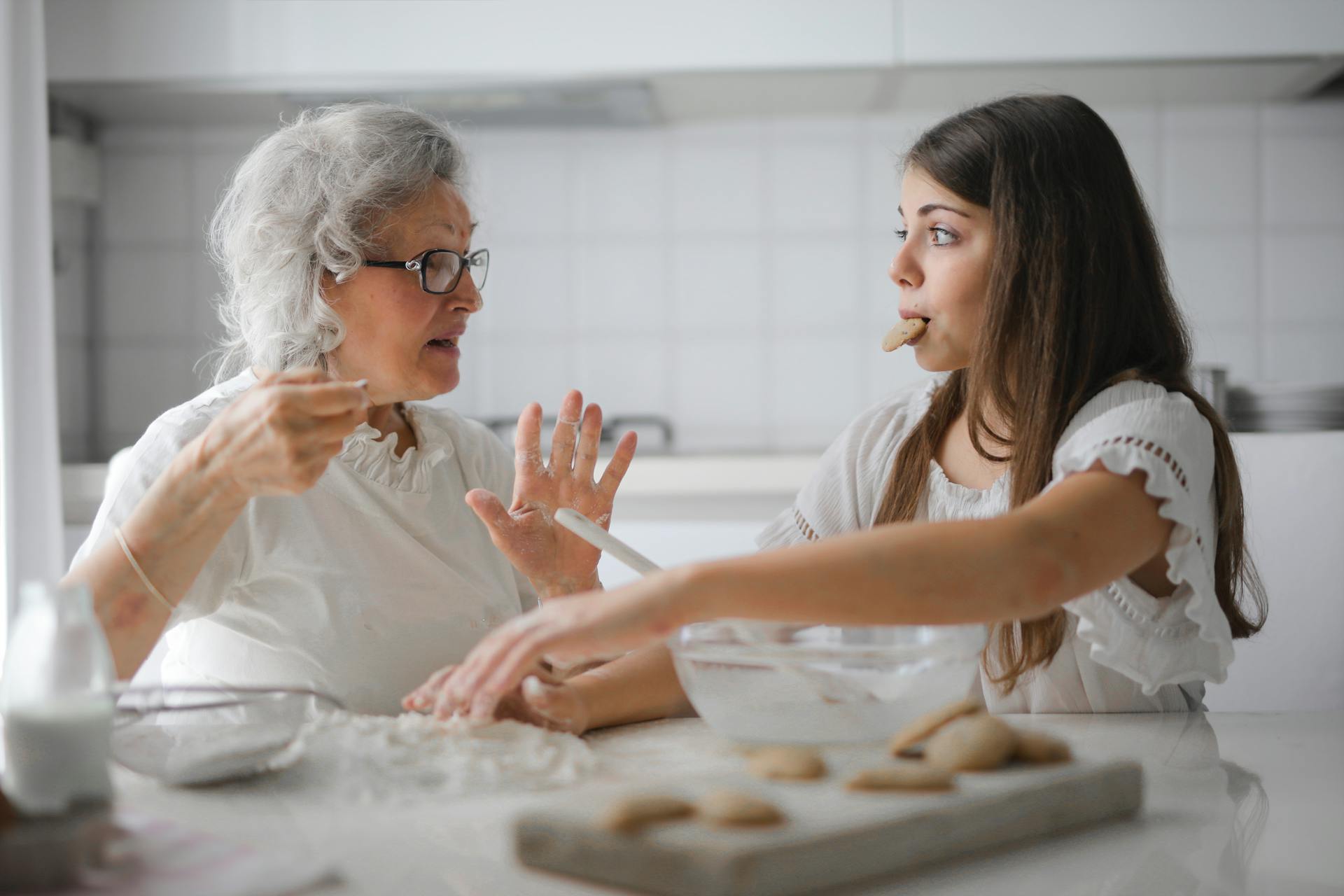 A grandmother talking to her granddaughter as the girl eats cookies | Source: Pexels