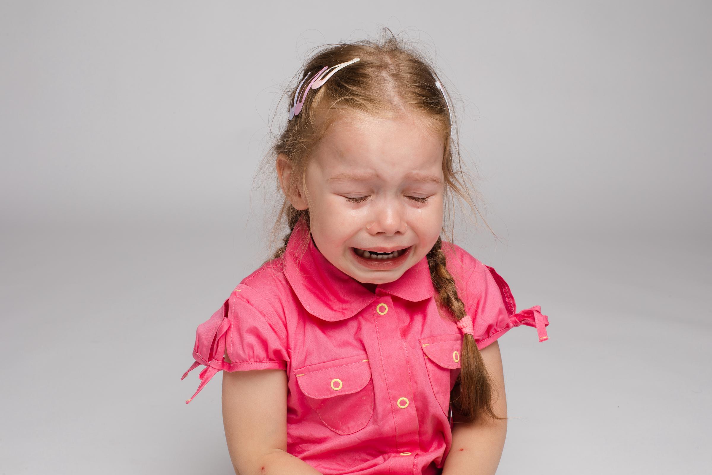 A crying girl in a pink dress | Source: Freepik