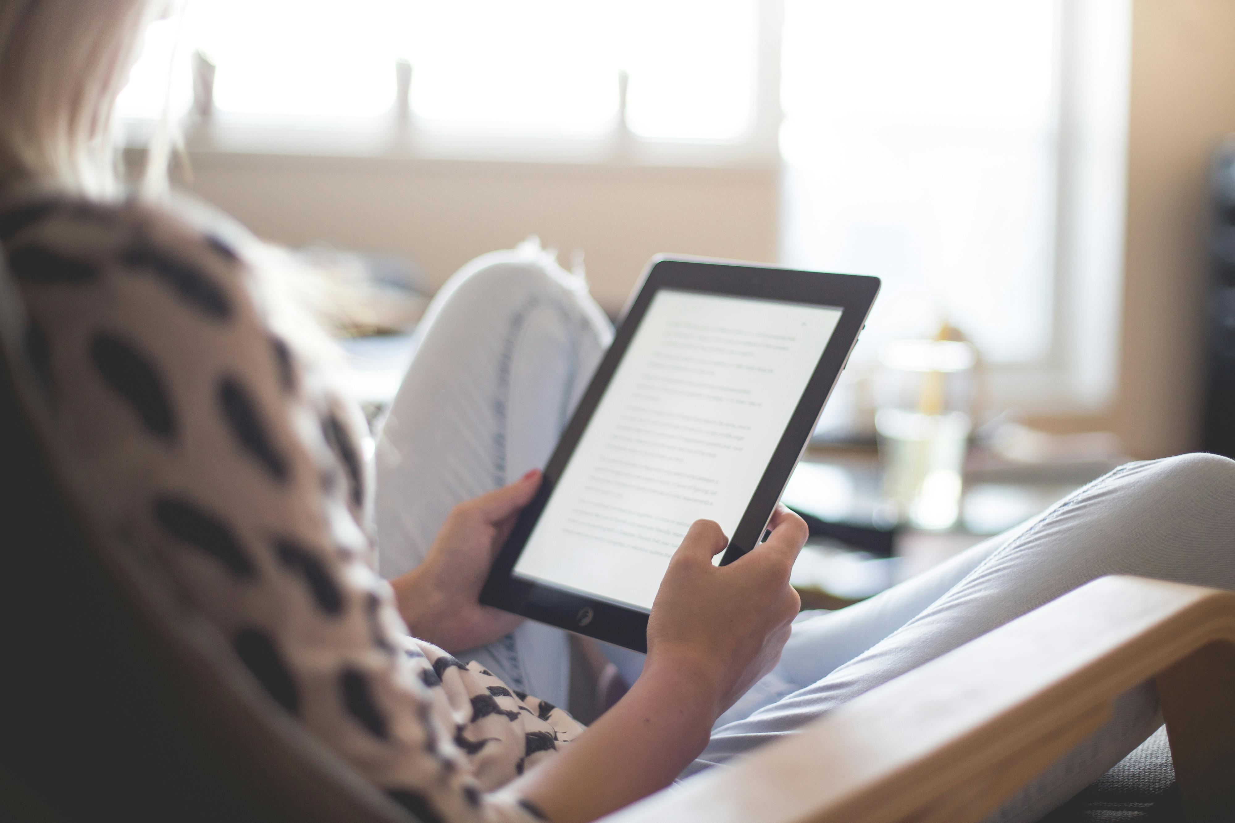 A woman sitting on a chair while using an Ipad | Source: Pexels