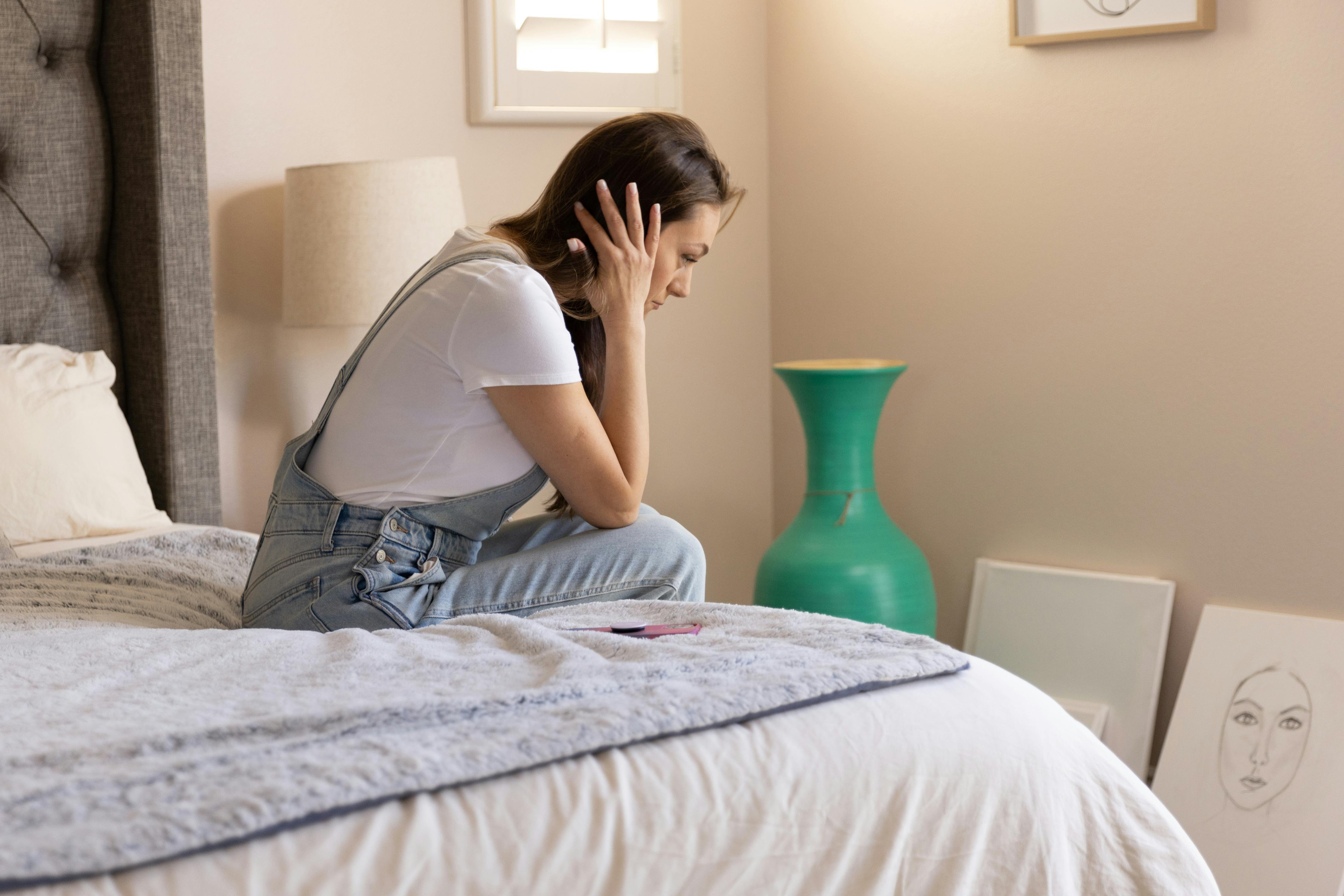 A worried woman sitting on the edge of the bed | Source: Pexels