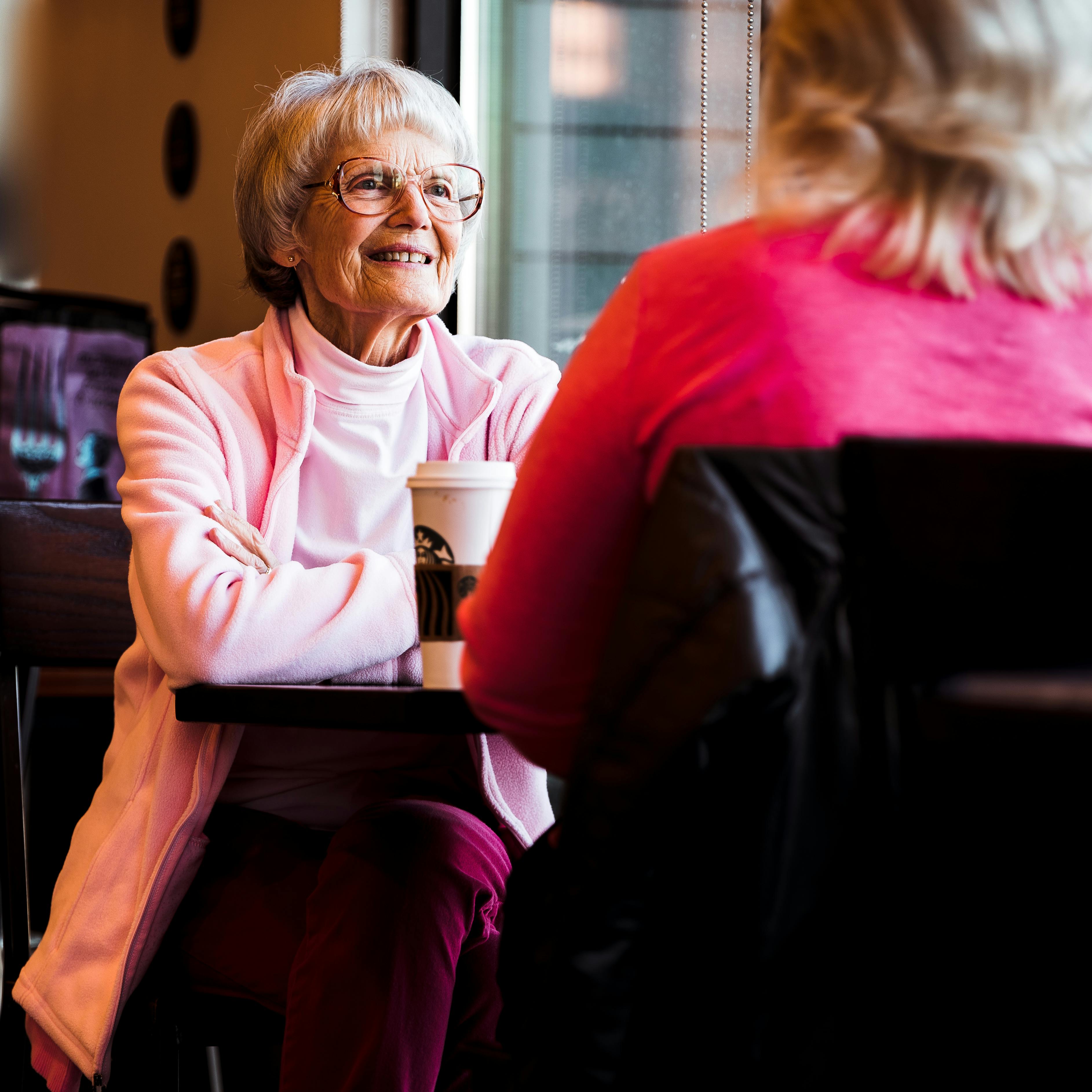 Two happy women sitting by a table | Source: Pexels