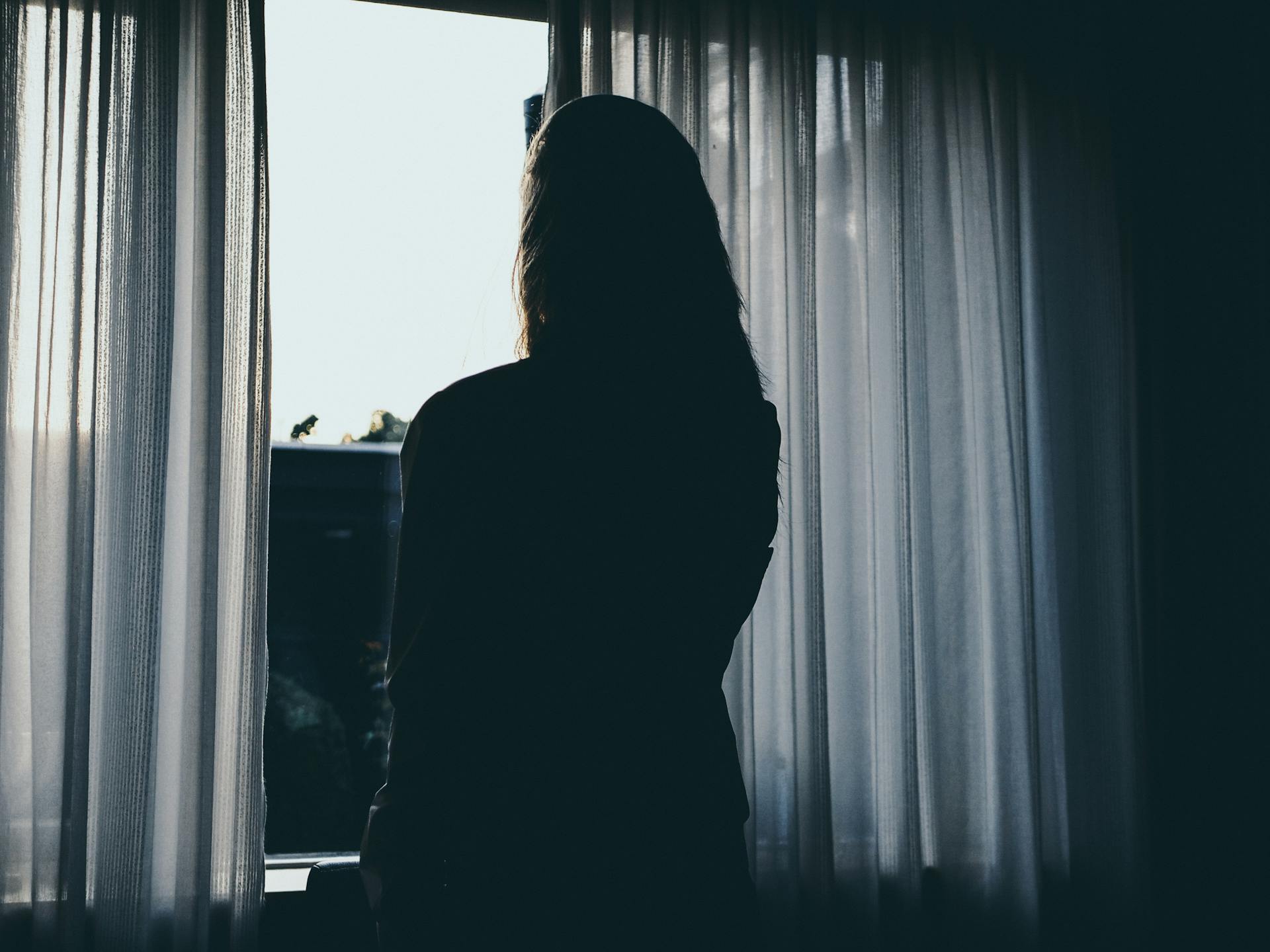 A woman looking outside a window | Source: Pexels