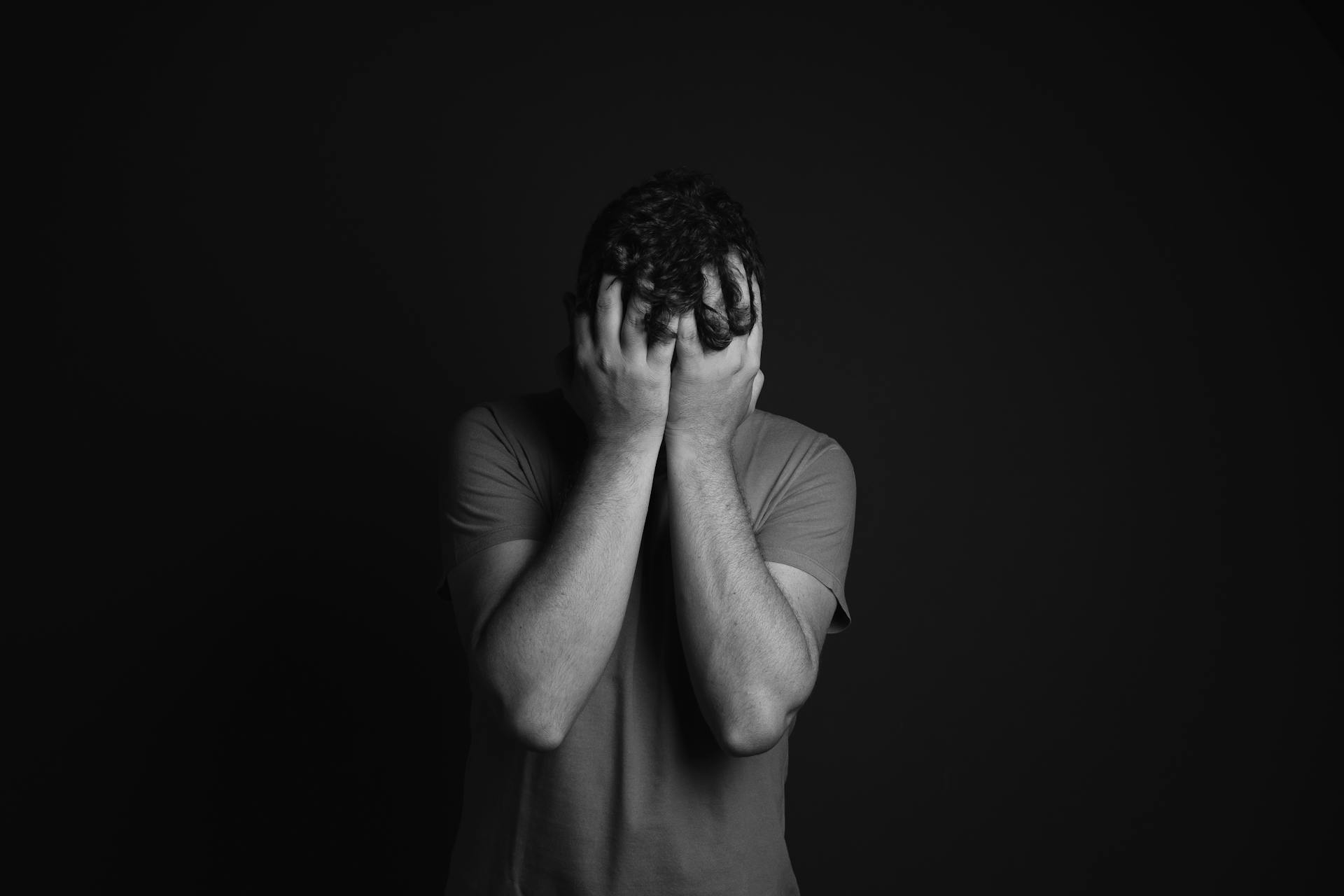 Grayscale of a man covering his face | Source: Pexels