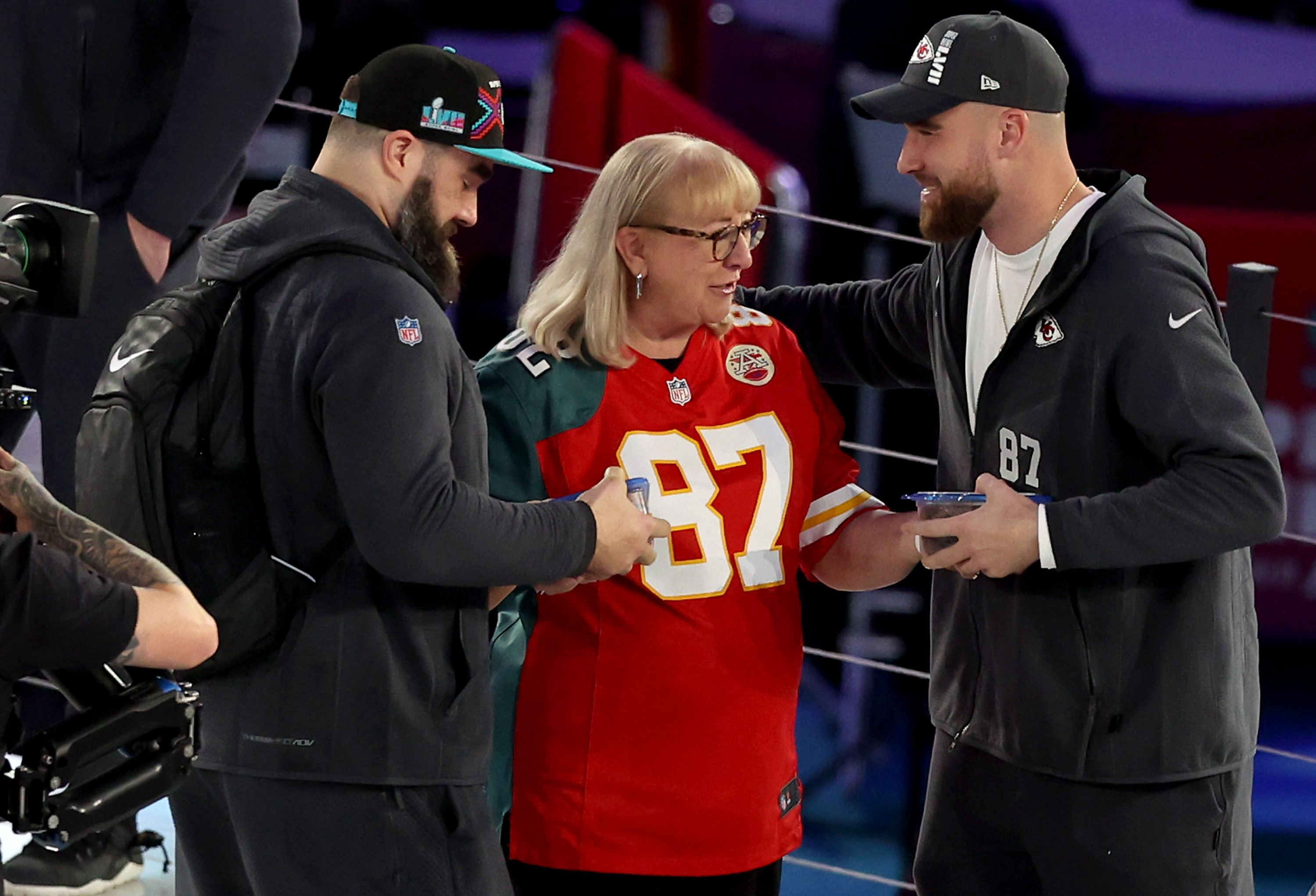 Donna Kelce gives cookies to her sons Jason Kelce (L) and Travis Kelce (R) during Super Bowl LVII Opening Night presented by Fast Twitch at Footprint Center in Phoenix, Arizona, on February 6, 2023 | Source: Getty Images